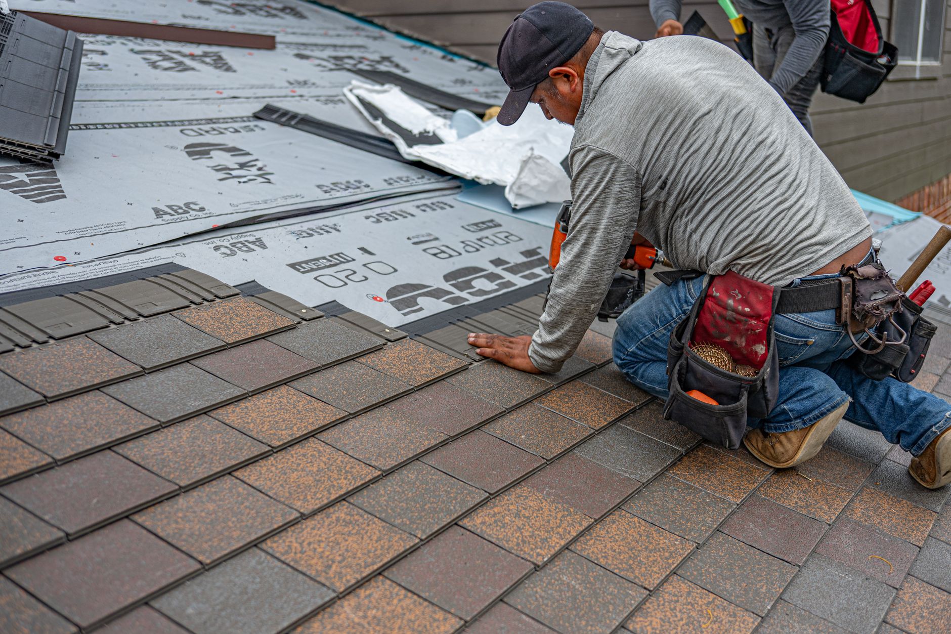 Roofing professional installing architectural shingles over synthetic underlayment